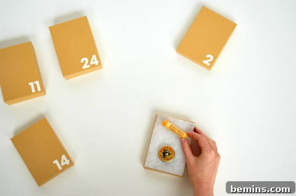 A hand holds a small object next to tan boxes with numbers on them.