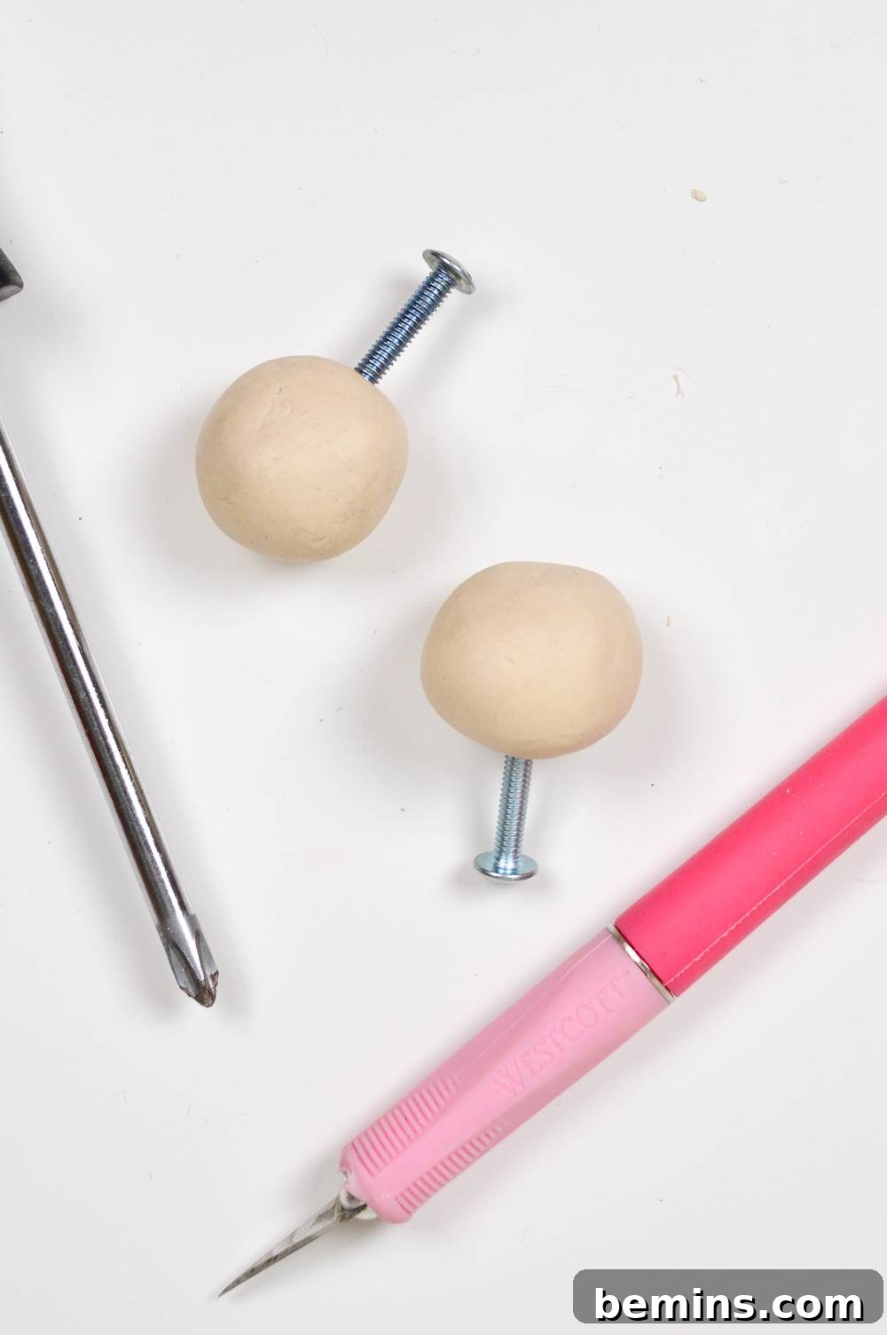 Two clay balls with screws inserted, ready for shaping.