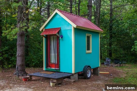 Tiny Houses: Sustainable Living for Everyone 4 A colorful tiny house mounted on blocks with tires, situated in a wooded area, highlighting the potential for off-grid living.