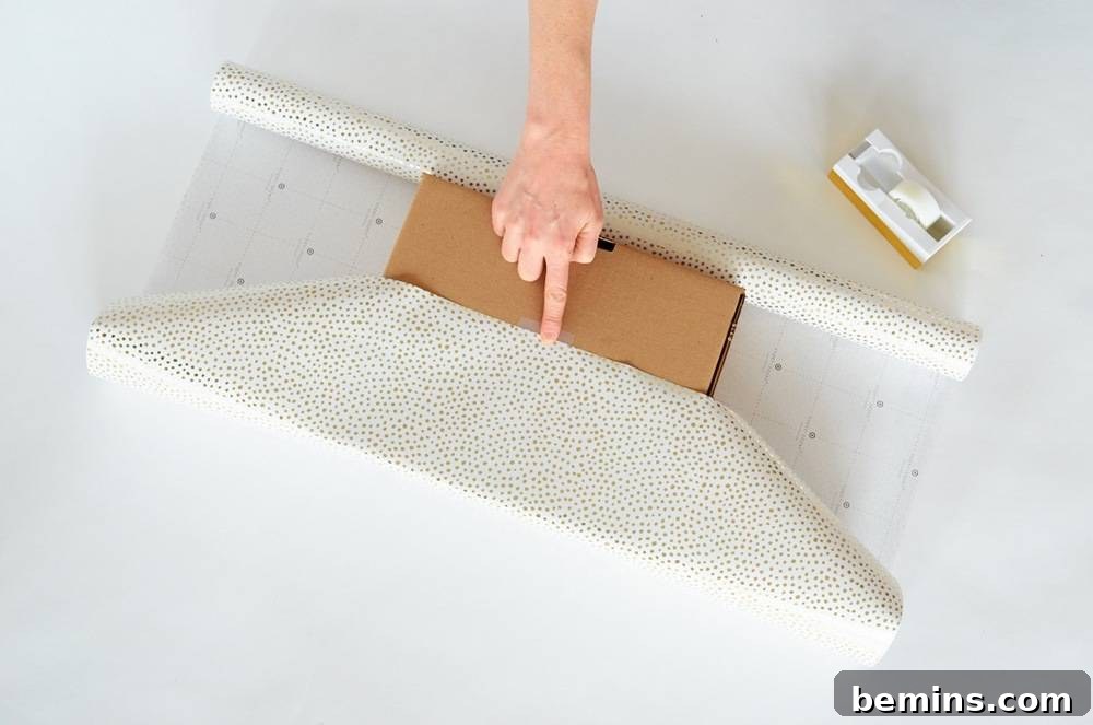 Person Placing a Cardboard Box on the Gift Paper and Ready to Pack It Securely