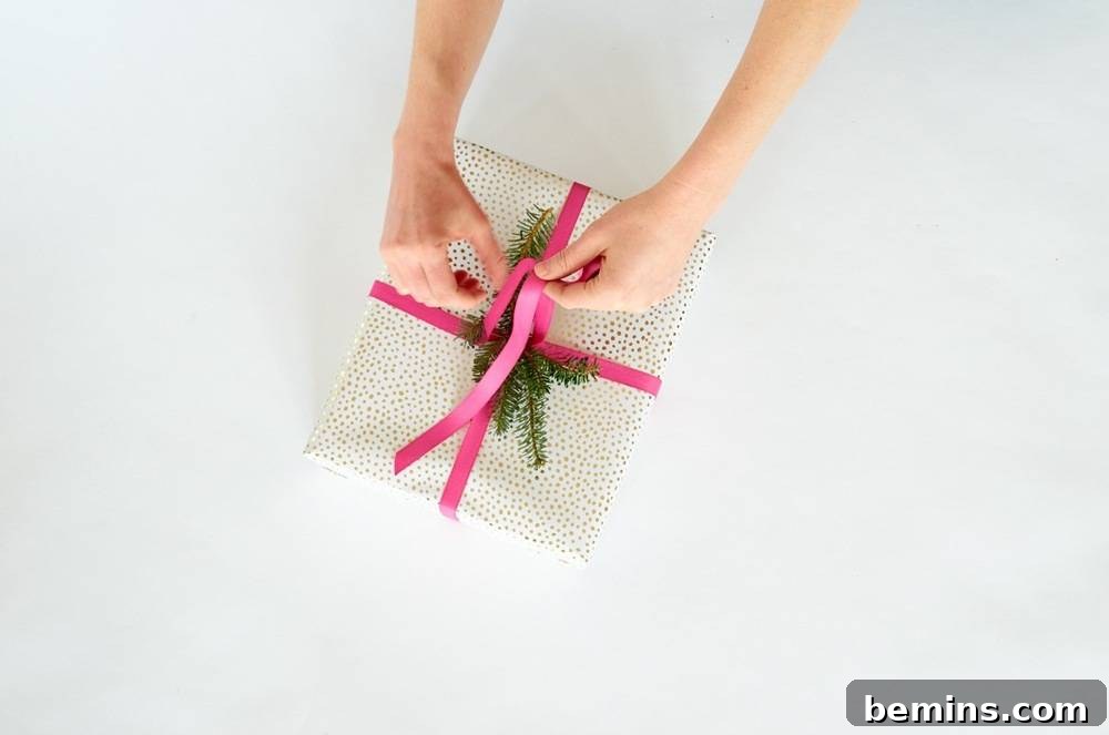 A Pair of Hands About to Finish Tying a Pink Ribbon Around a Small Box Wrapped in Dotted Wrapping Paper