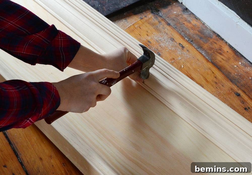 Crafting Your Own Fireplace Mantel 11 Securing crown molding with nails and an awl on DIY mantel