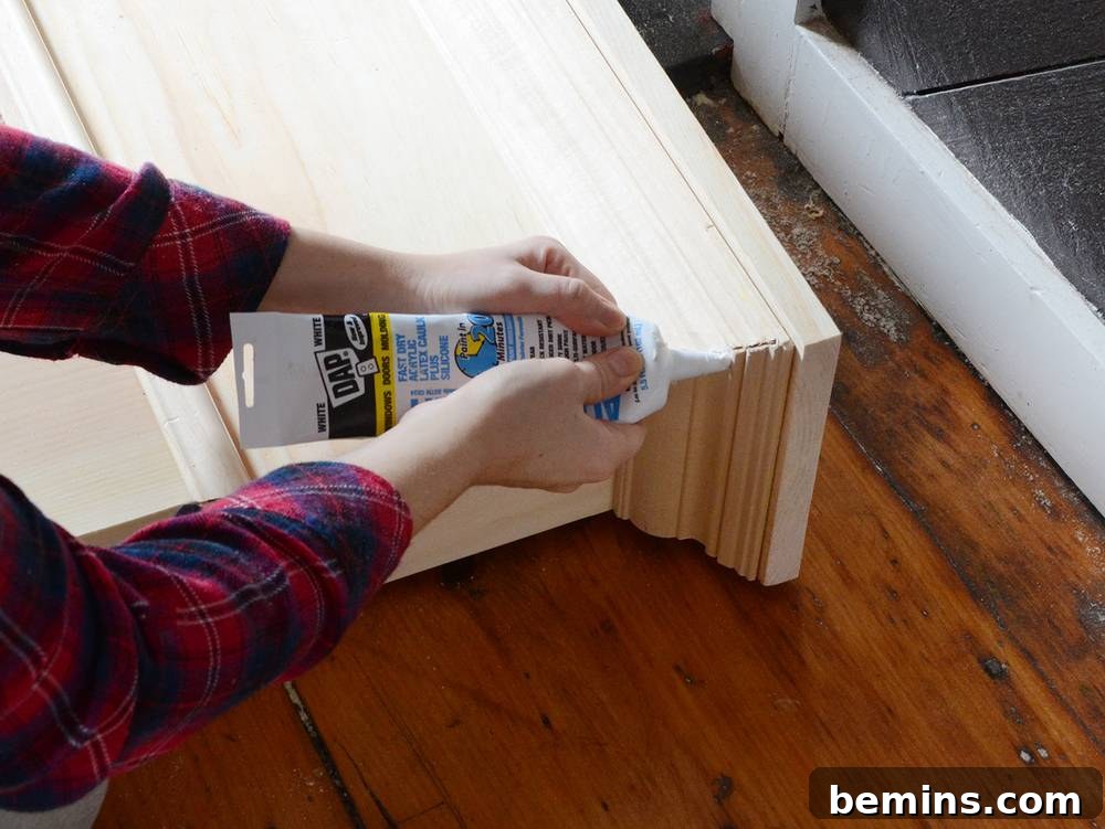 Crafting Your Own Fireplace Mantel 15 Filling gaps in the DIY wooden mantel with caulk for a seamless finish