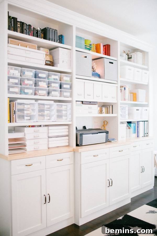 30 Impeccably Organized Studios for Creative Genius 28 Neatly organized storage wall with color-grouped books and light-colored storage boxes.