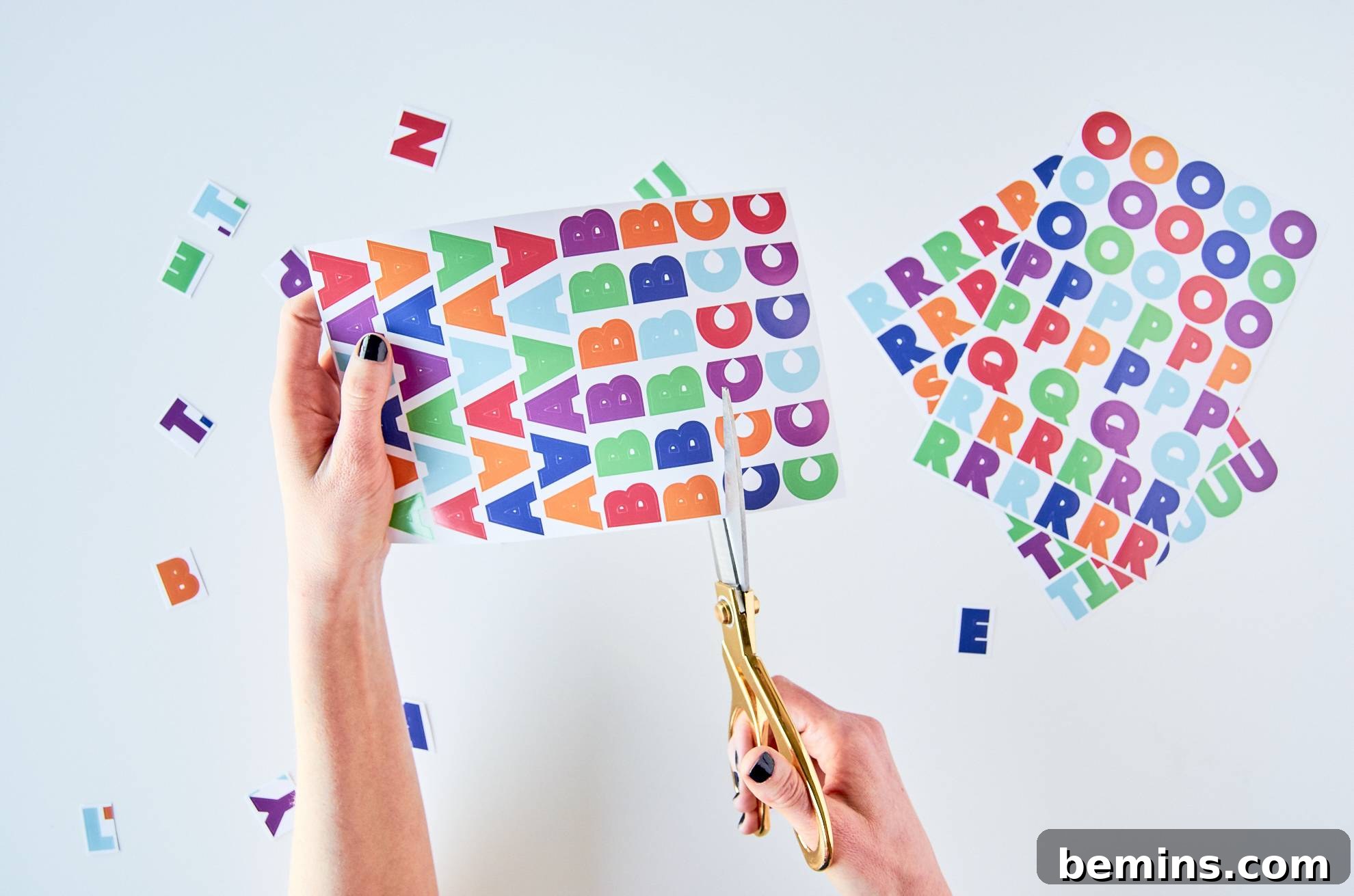 A woman cuts out colorful letters from a sheet of stickers.