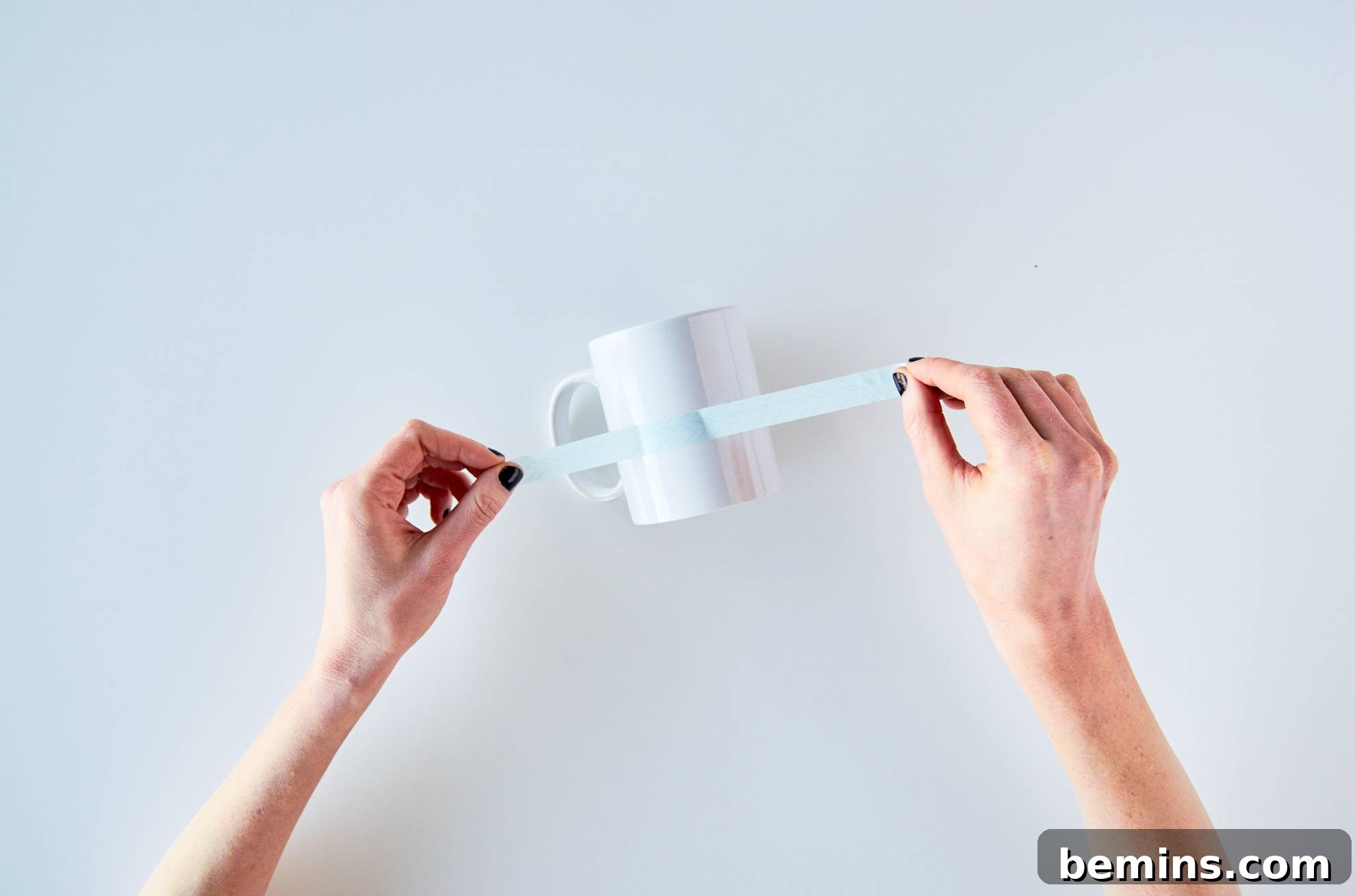 A person putting a sticker on a white mug.