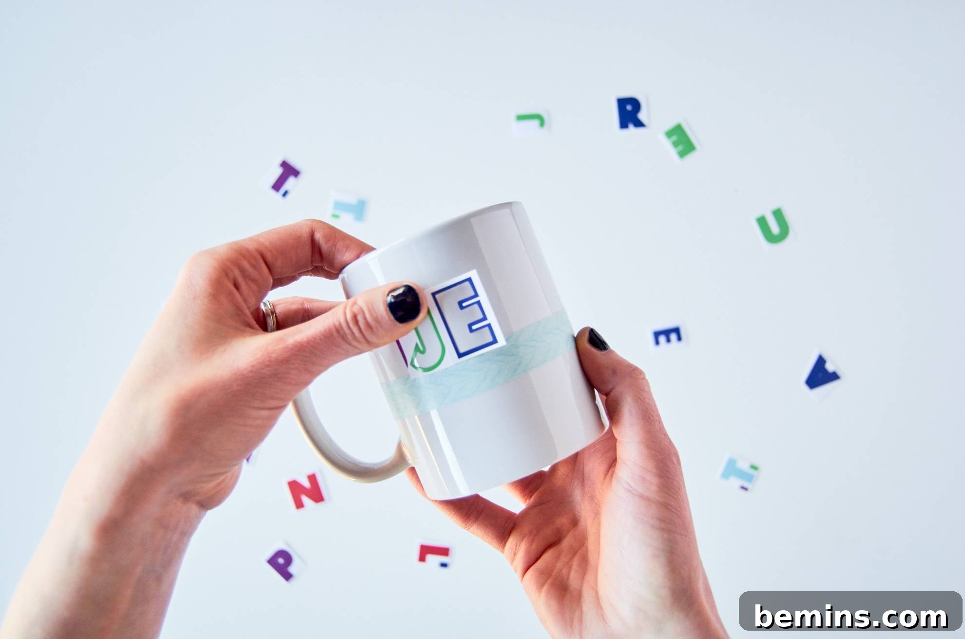 A woman placing lettering on a mug for decoration.