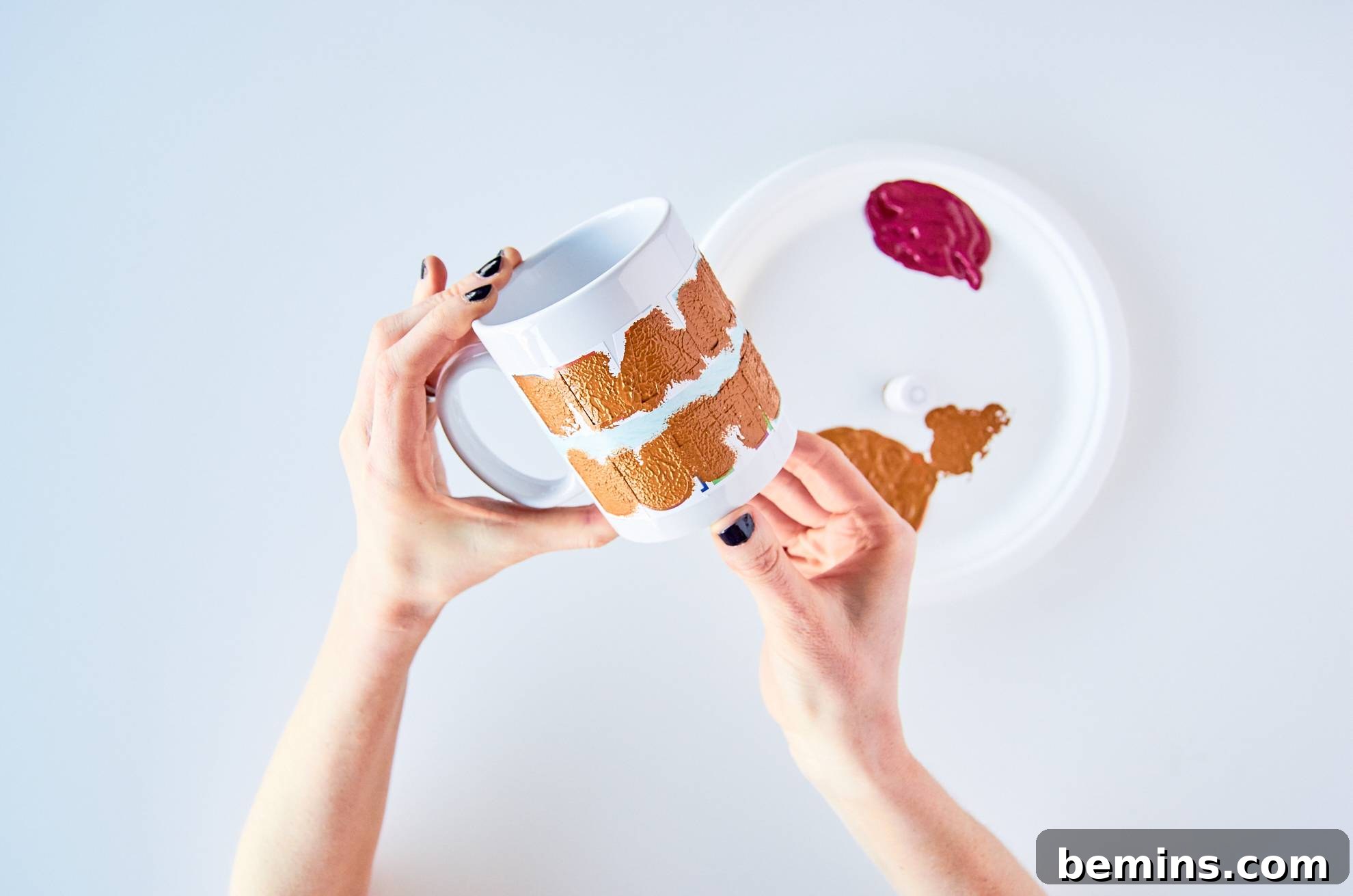 Woman painting a design on a white mug.