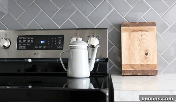 A modern kitchen sink area with a clean aesthetic and a hint of the herringbone backsplash.