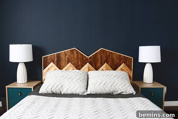 A serene minimalist master bedroom featuring a handmade mountain headboard, a charcoal blue accent wall, and neutral bedding from Anthropologie.
