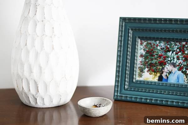 Close-up of a stylish bedside table featuring an IKEA hack, simple decor, and a Crate & Barrel lamp.