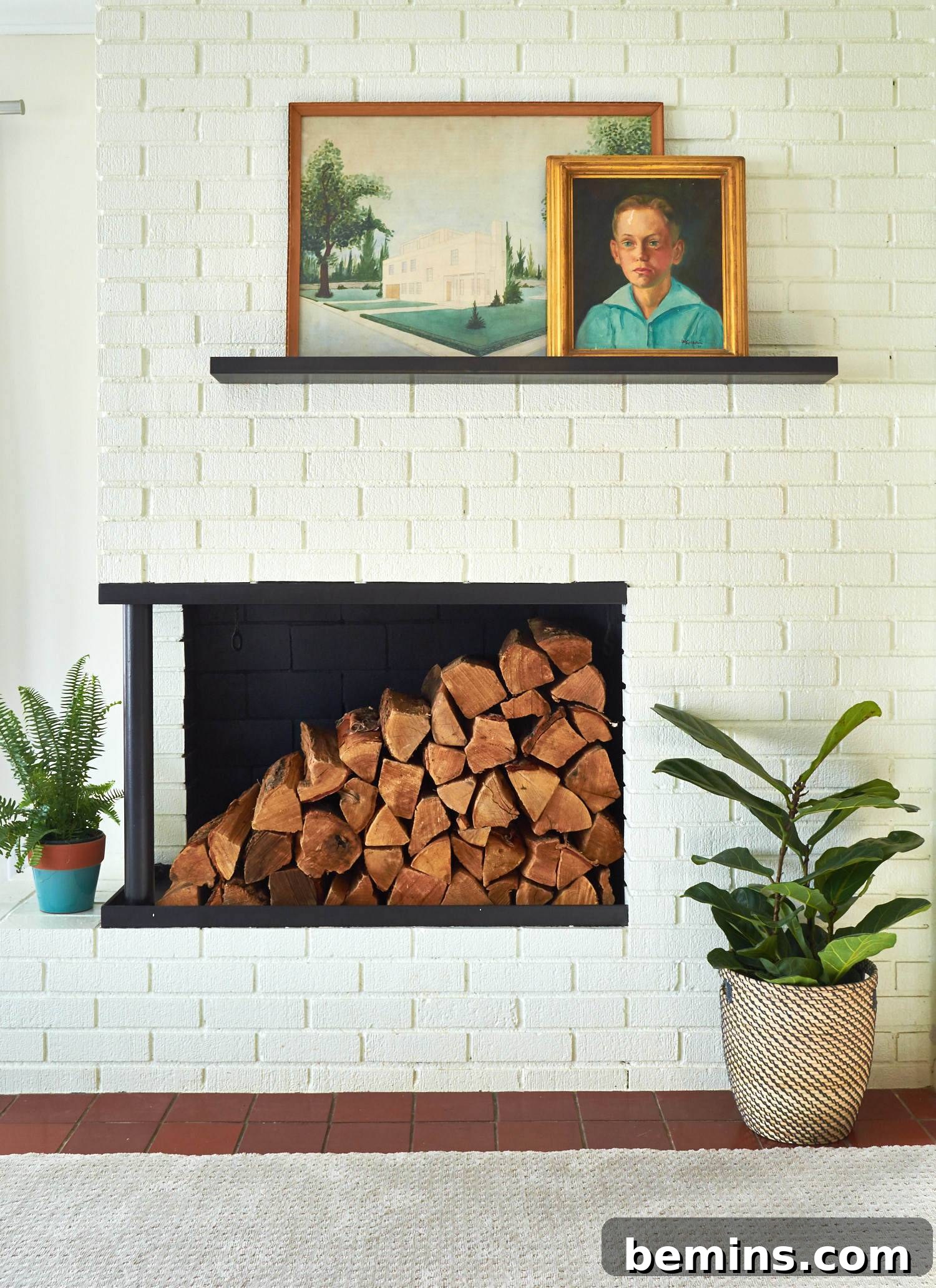 Fireplace built inside a brick wall with a wood shelf above that holds two framed pictures.