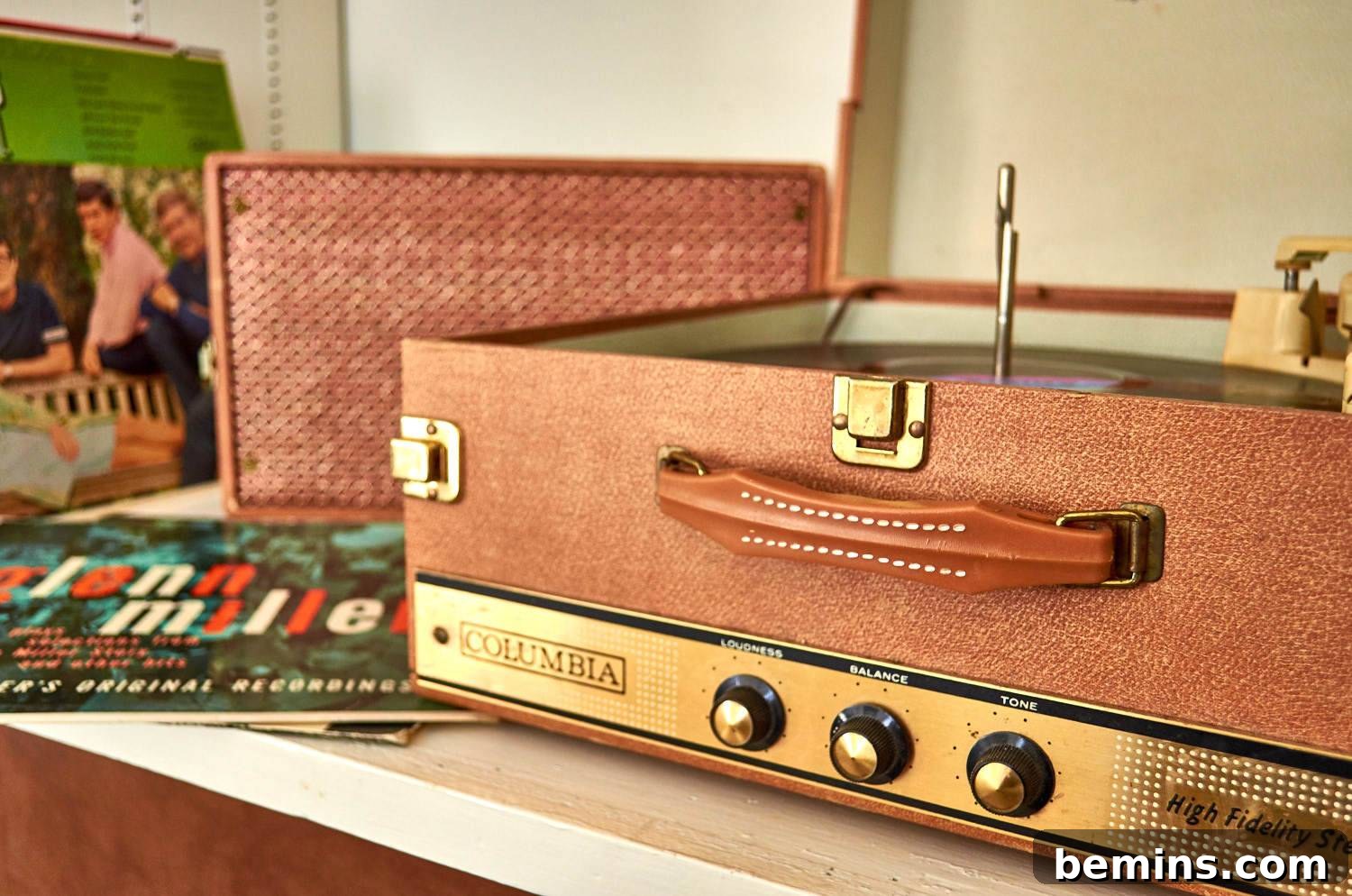 Vinyl records by vintage record player built into a brown suitcase.