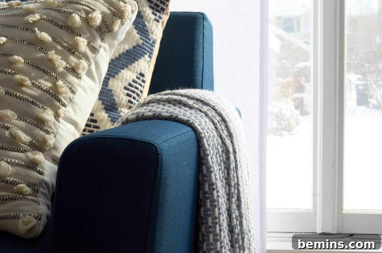 A closeup of a couch with two pillows and a blanket.