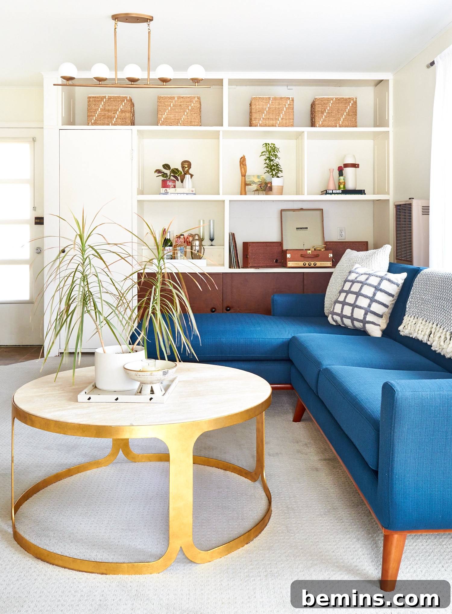 Clean and modern living room with blue couch, round coffee table, and white shelf.