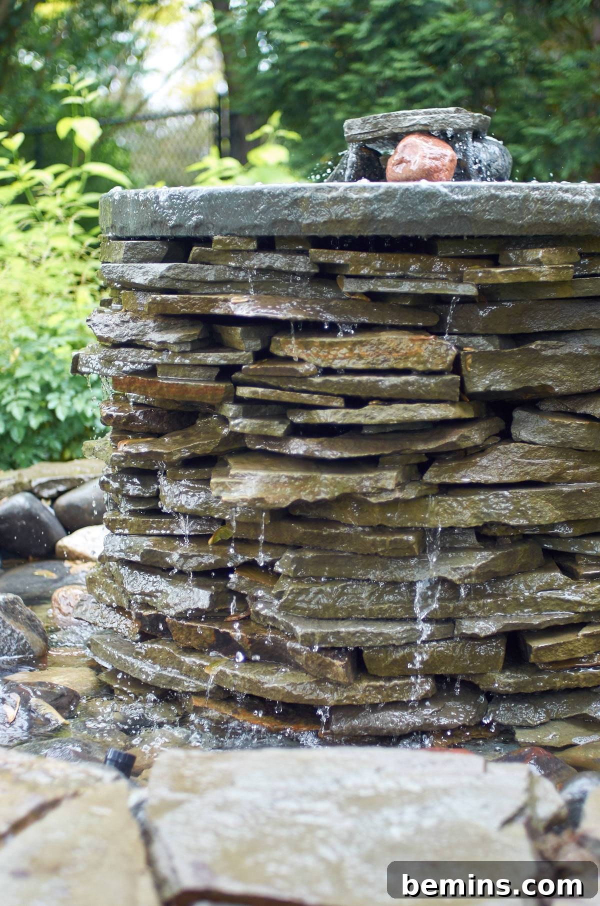 Creating a Backyard Oasis: A DIY Pond and Fountain Project 15 Water elegantly cascading down a stone fountain, creating a mesmerizing visual effect.