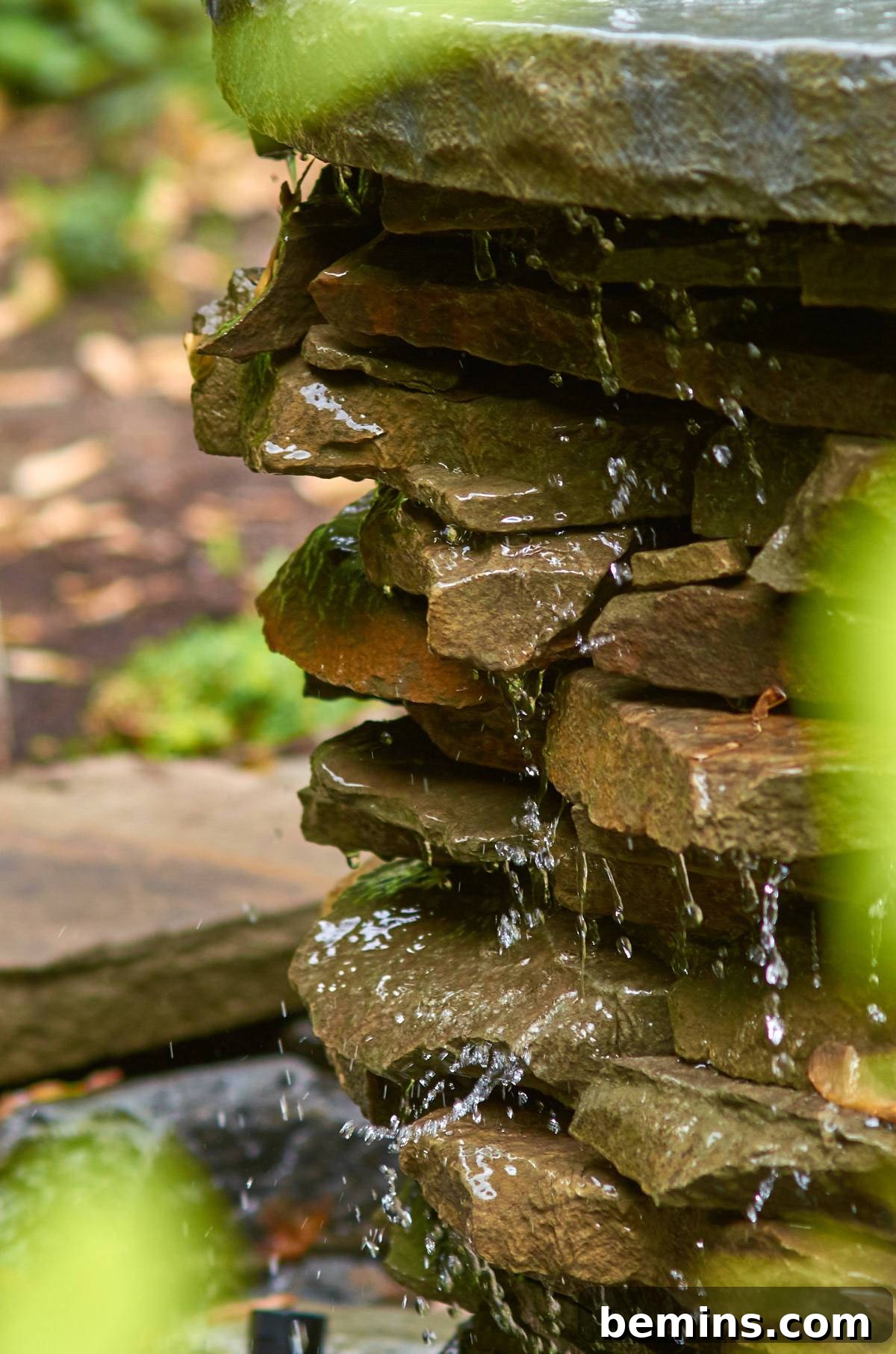 Creating a Backyard Oasis: A DIY Pond and Fountain Project 17 Water gracefully flowing over a stack of brown stones, creating a miniature waterfall.