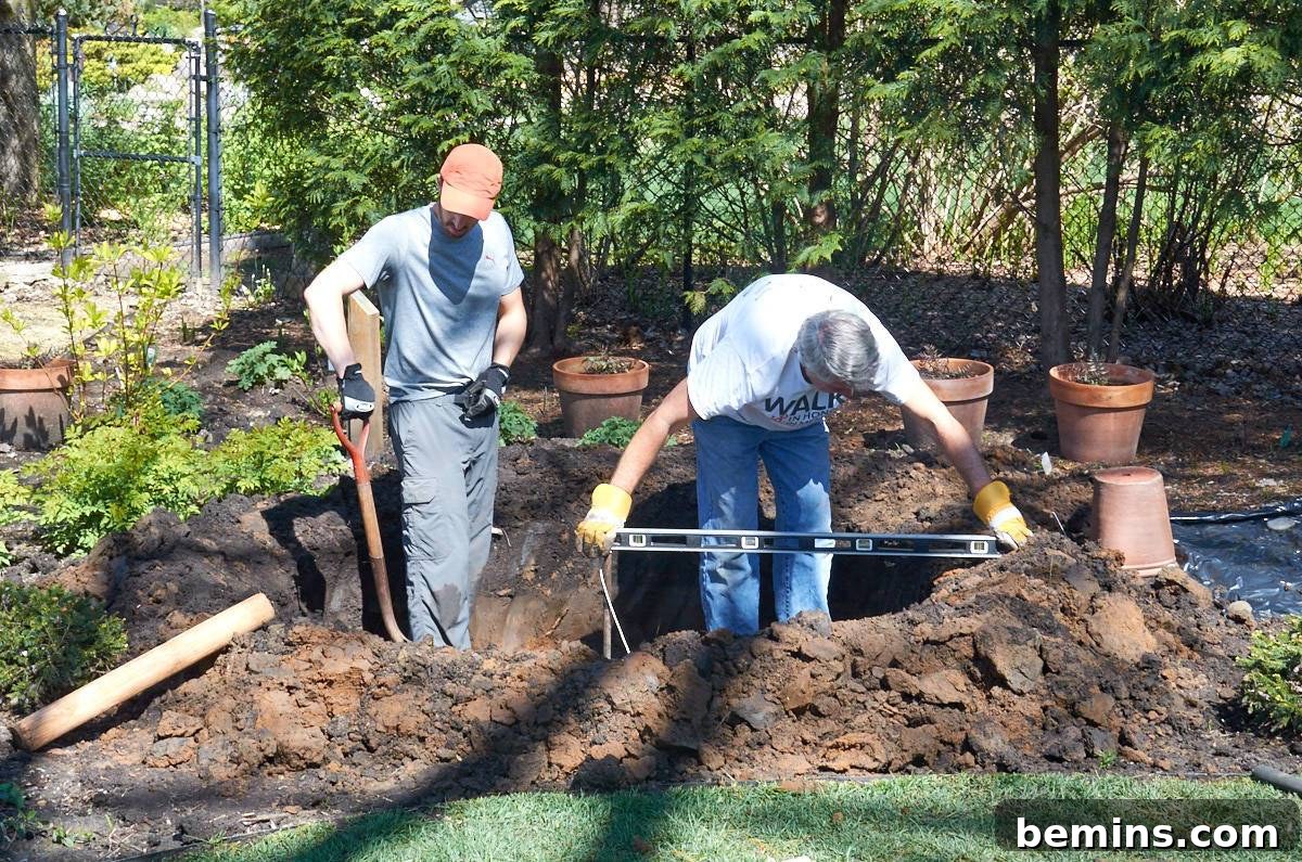 Creating a Backyard Oasis: A DIY Pond and Fountain Project 6 Two men working together to dig and level the base of the backyard pond.