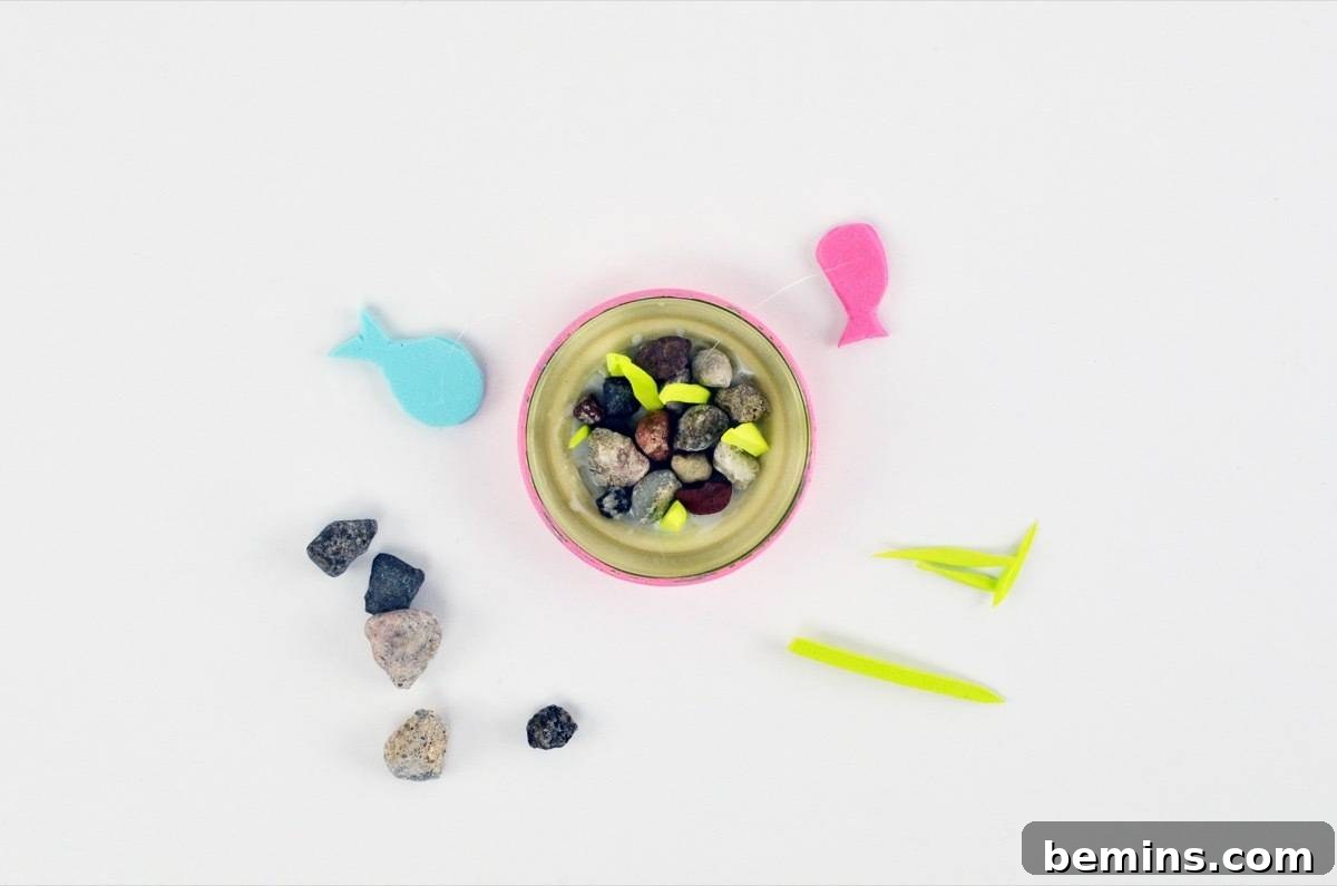 Gluing foam fish and rocks inside the jar lid