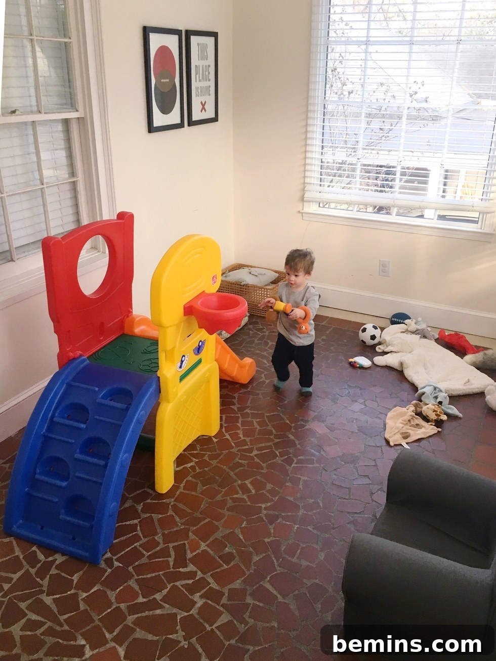 A child enjoying a colorful slide in a transformed living room playroom.