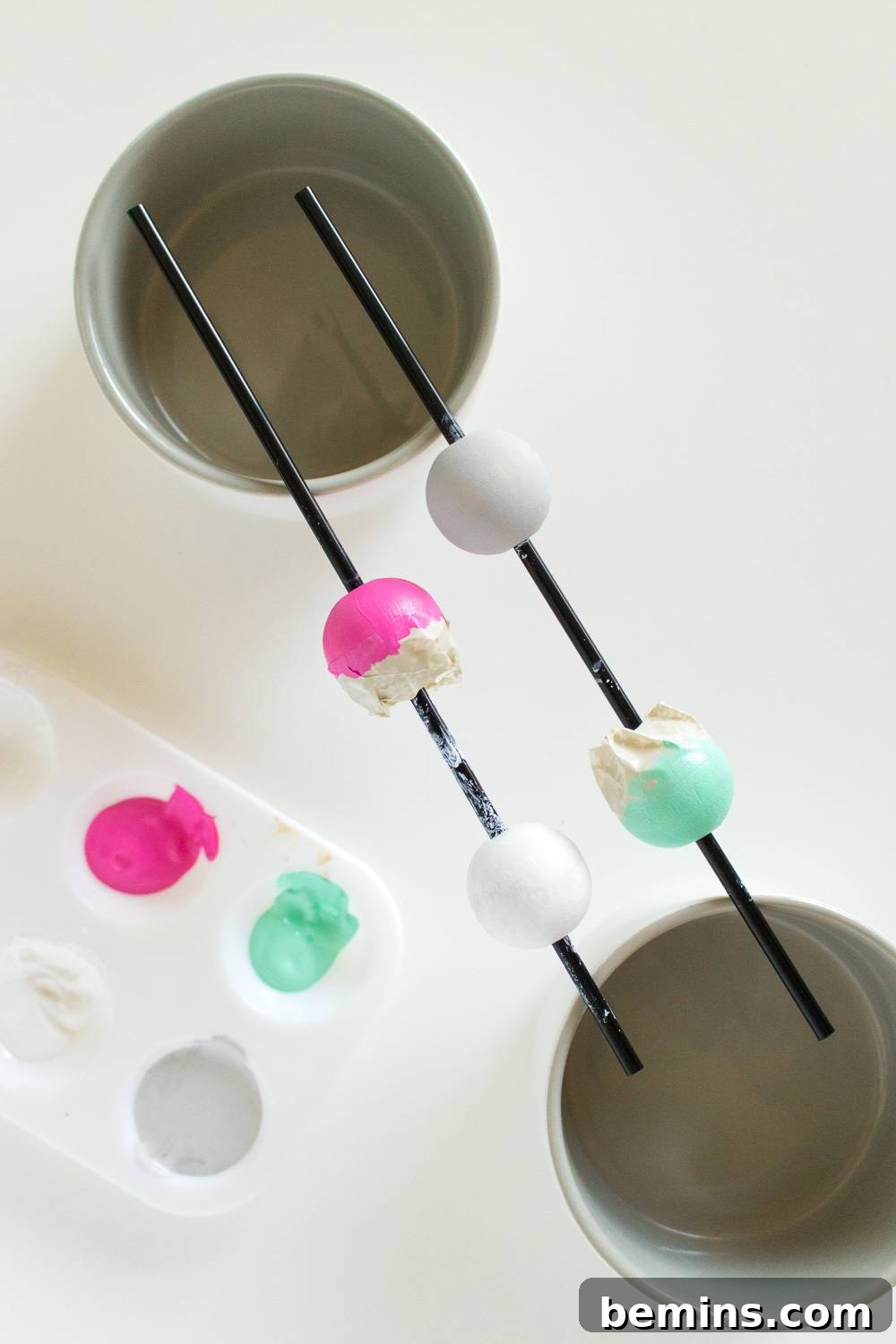 Painted wooden beads drying on sticks