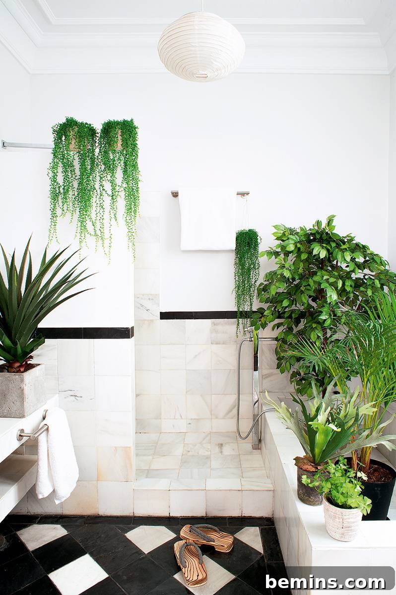 17 Stunning Bathrooms That Embrace the Shower Plant Trend 15 A bathroom with a black and white floor and greenery everywhere.
