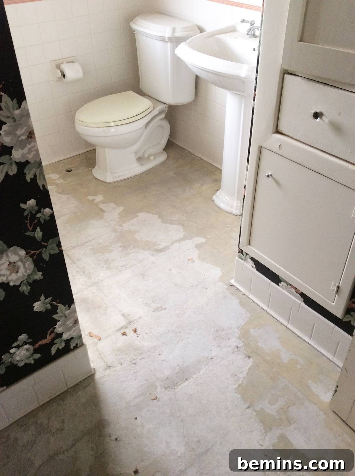 The bathroom floor partially scraped, revealing old mortar and a found bandage.
