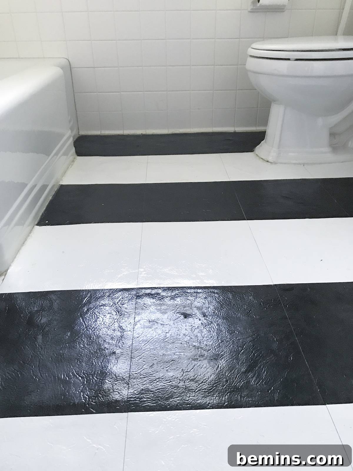 Cutting the vinyl tiles with scissors to fit the edges of the bathroom floor.