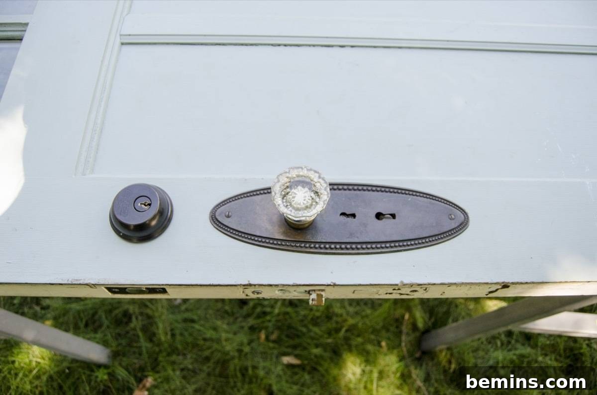 A grey door resting horizontally, showcasing a crystal door knob and prepped for the painting process.