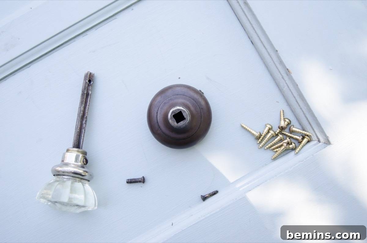 A close-up of the drawer pull and screws, carefully organized after removal from the door.