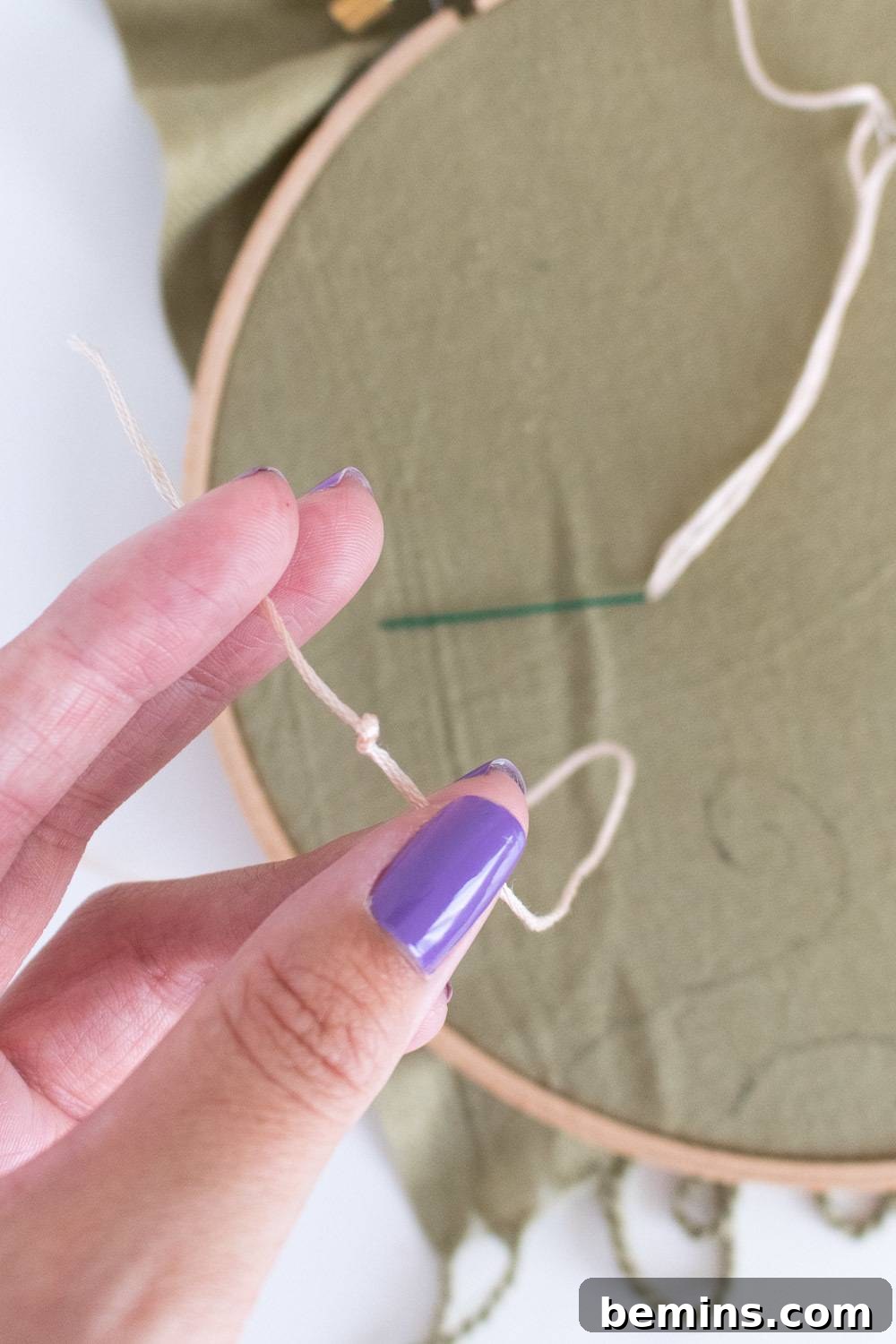A close-up of a woman's hand meticulously holding a loop while engaged in needlecraft