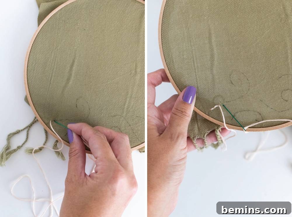 A person with purple fingernails delicately executing cross-stitching on fabric