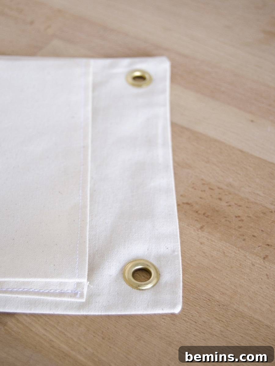 Adding grommets to the top of the DIY hanging fabric planter for easy display