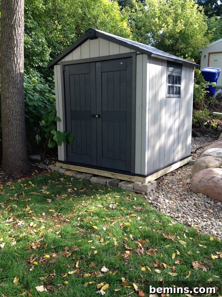 A completed backyard storage shed with light colored walls and dark double doors.