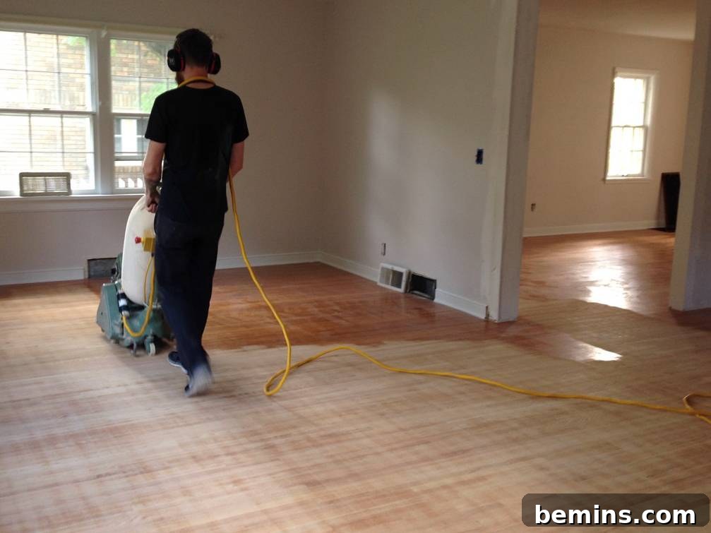 A professional refinishing hardwood floors with a floor sander.