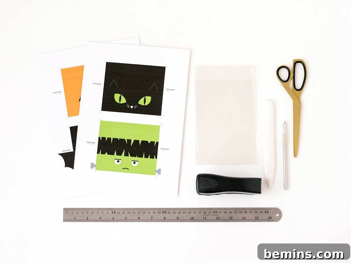 Materials for making Halloween treat bag toppers: ruler, craft knife, scissors, and printable designs