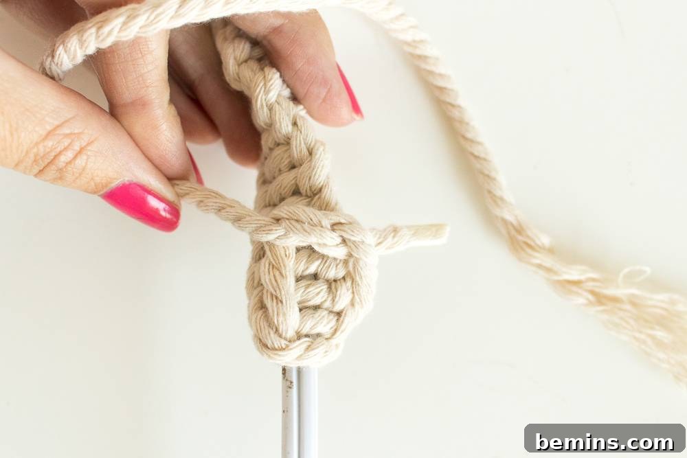 Close-up of a hand holding the macrame wrapped cord, showcasing the intricate pattern and texture of the macrame craft.