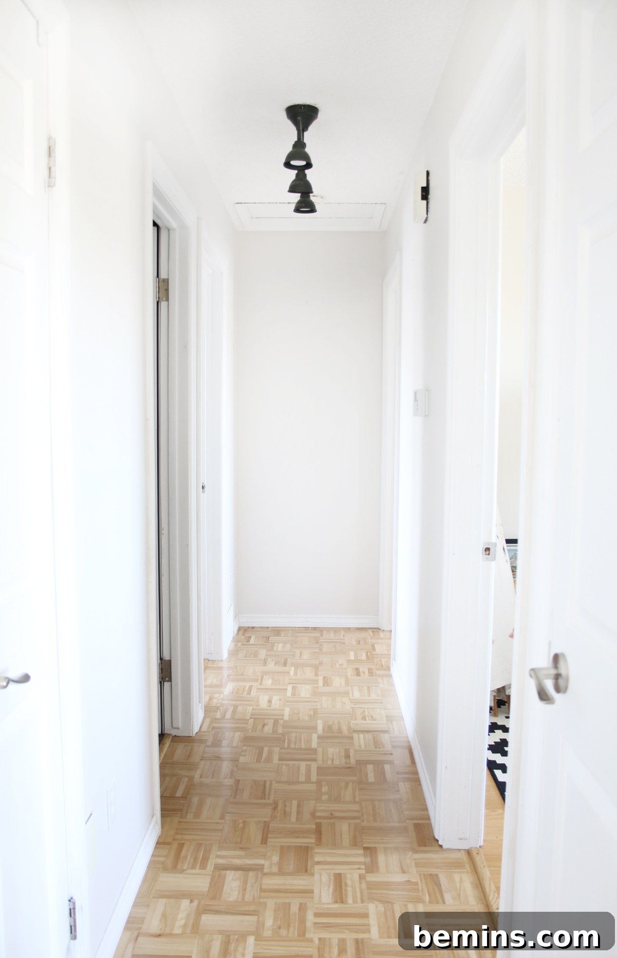 Interior hallway with brown tile floor and white walls. A beautifully renovated hallway featuring a clean, modern aesthetic.