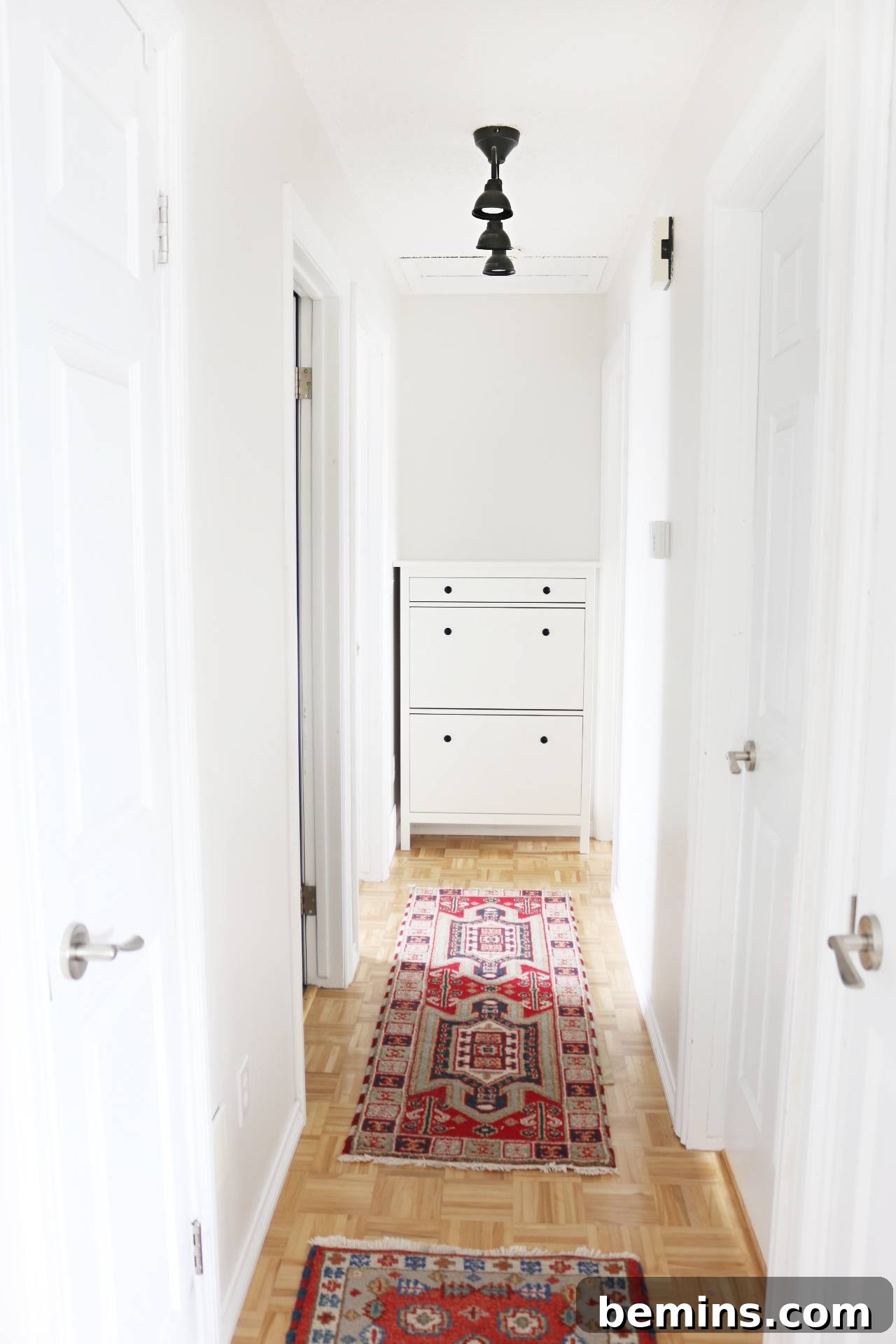 Two red rugs sitting on a floor in a hallway with white walls. After the renovation, the hallway features bright white walls and colorful rugs for a modern Scandinavian look.