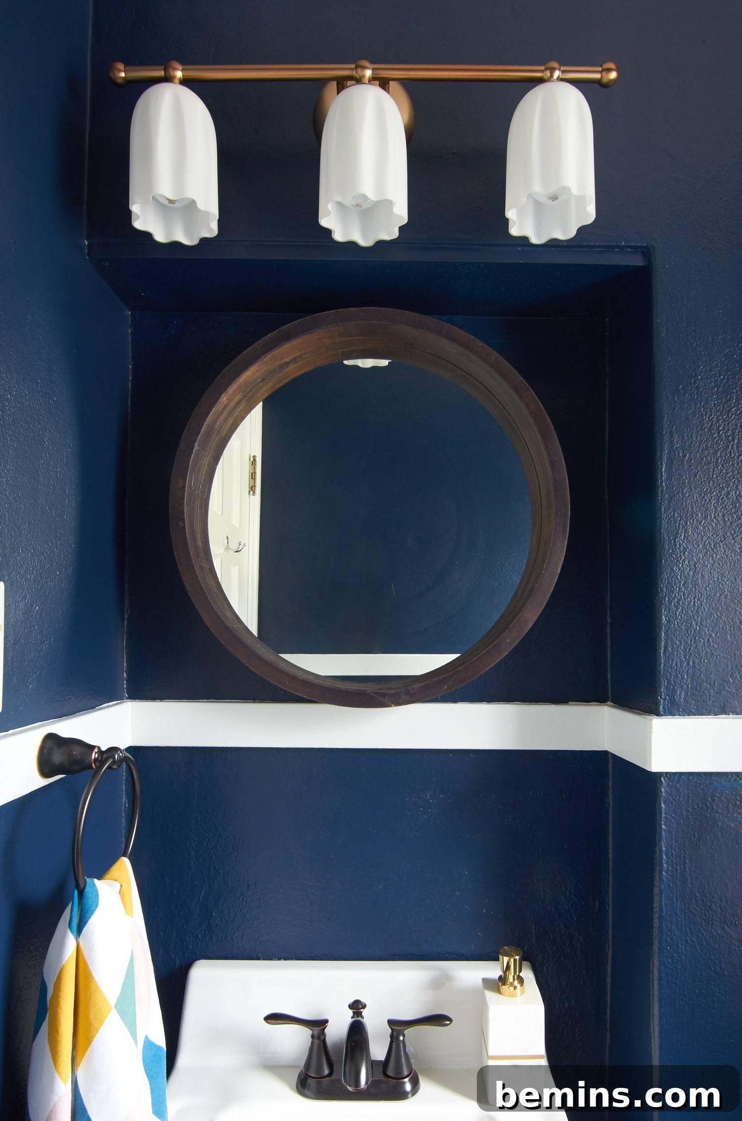 Gold vanity light with dark blue walls