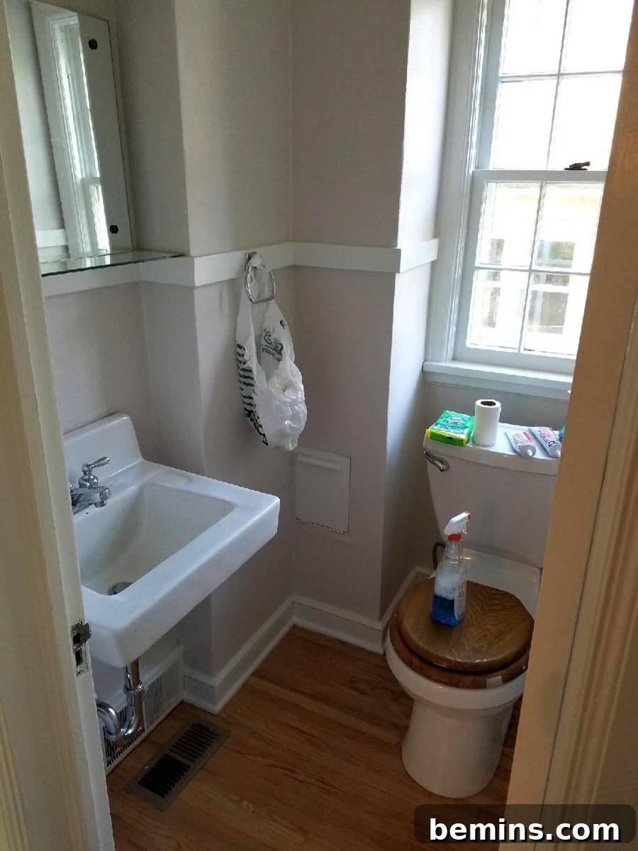 Tiny home bathroom with wood trim on the toilet seat and small mirror on the wall.