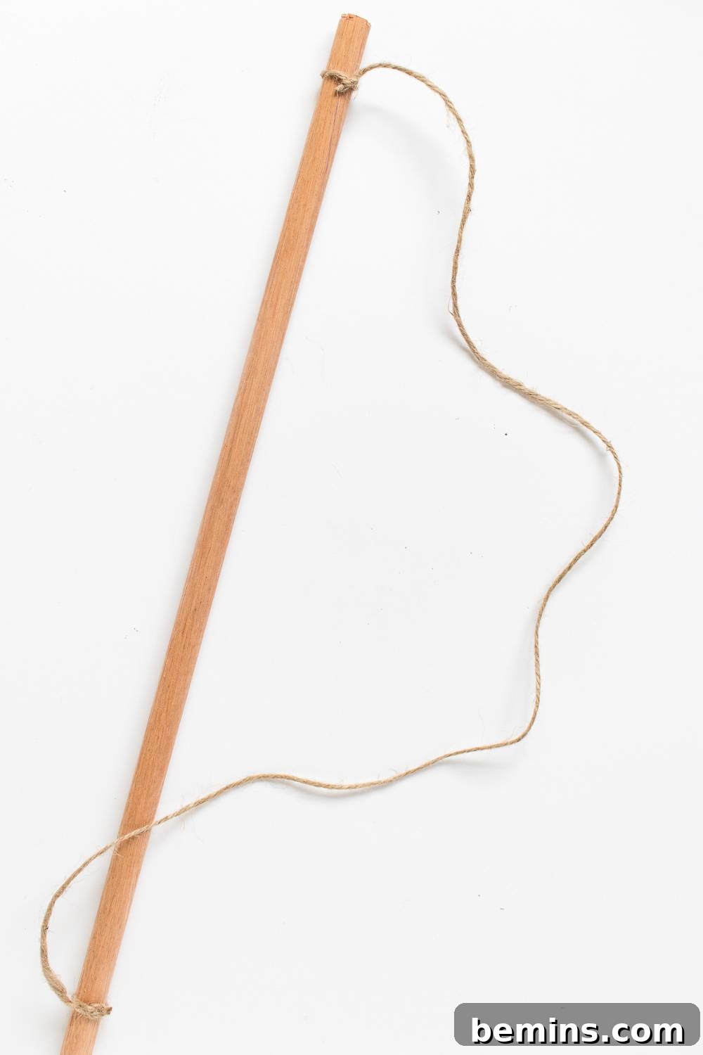 Close-up of a slender wooden stick with pieces of twine securely tied to each end, ready for hanging.