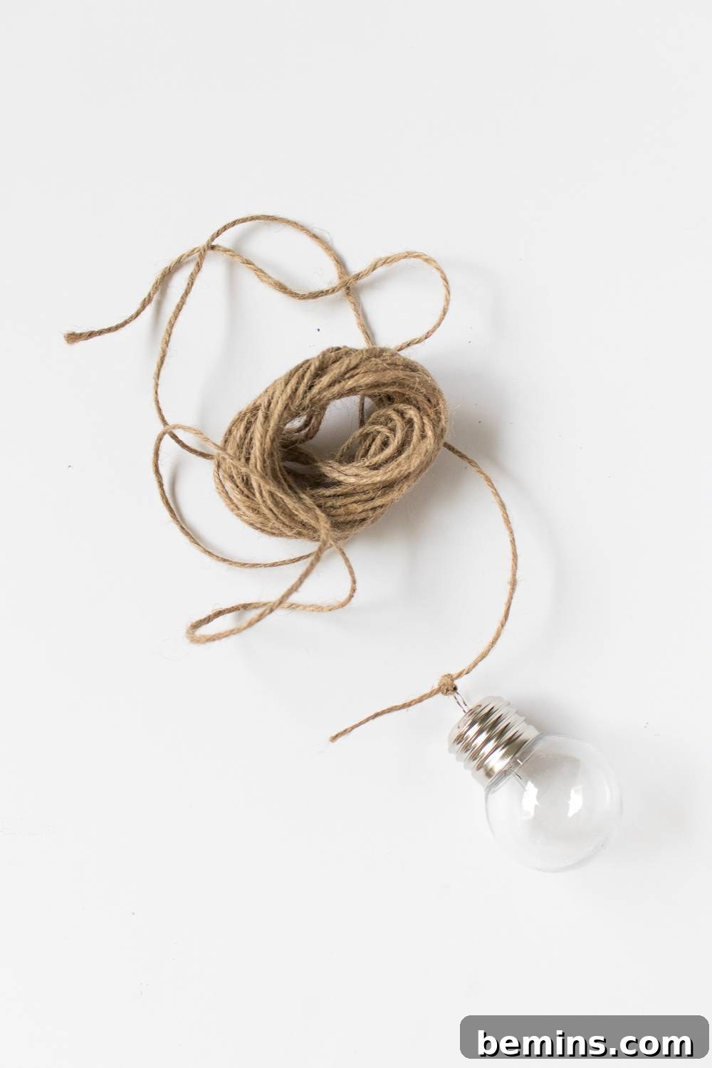 Close-up shot of a ball of natural brown twine resting on a white table, illuminated by a warm, inviting lightbulb.