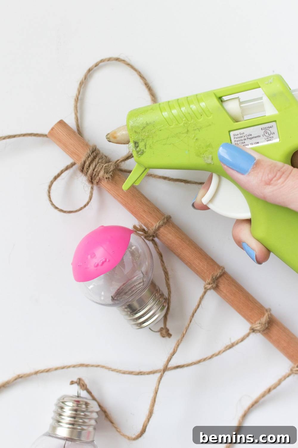 Close-up of a person's hand holding a green tool near a partially assembled craft project.