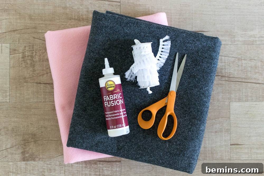 Tabletop scene featuring fabric pieces, glue, scissors, and fringe, the tools for a creative DIY project
