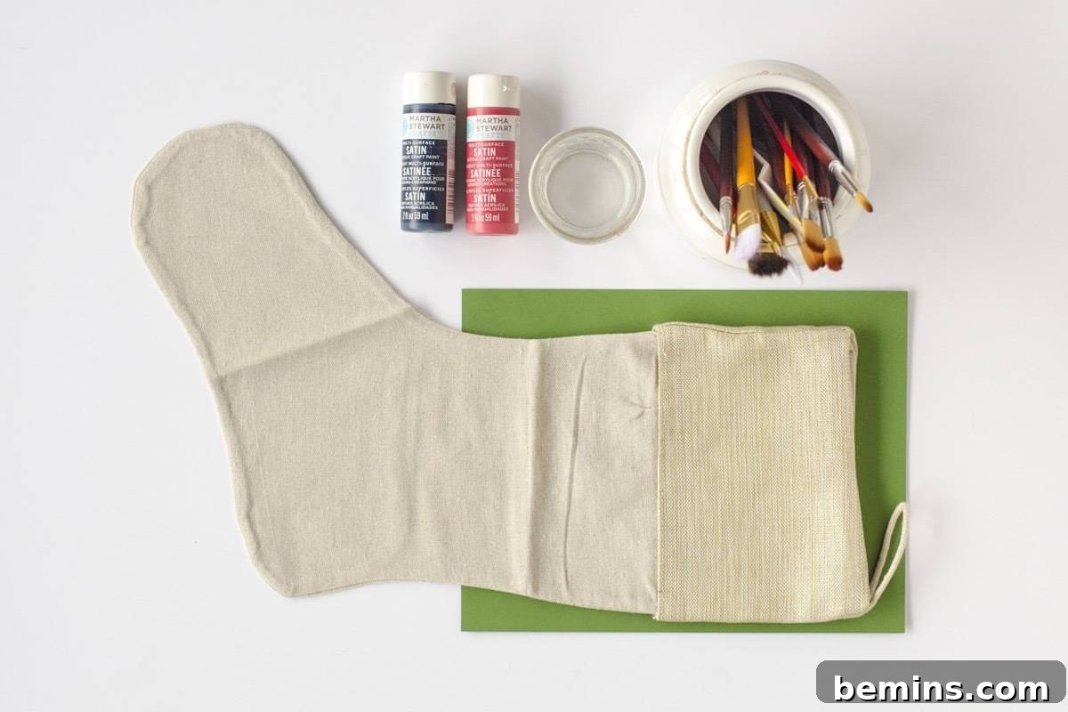 Materials needed to make these hand-painted Scandinavian stockings, including plain cotton stockings, acrylic paints, paintbrushes, and cardstock.