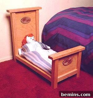 A doll lying in a wooden crib next to a regular bed