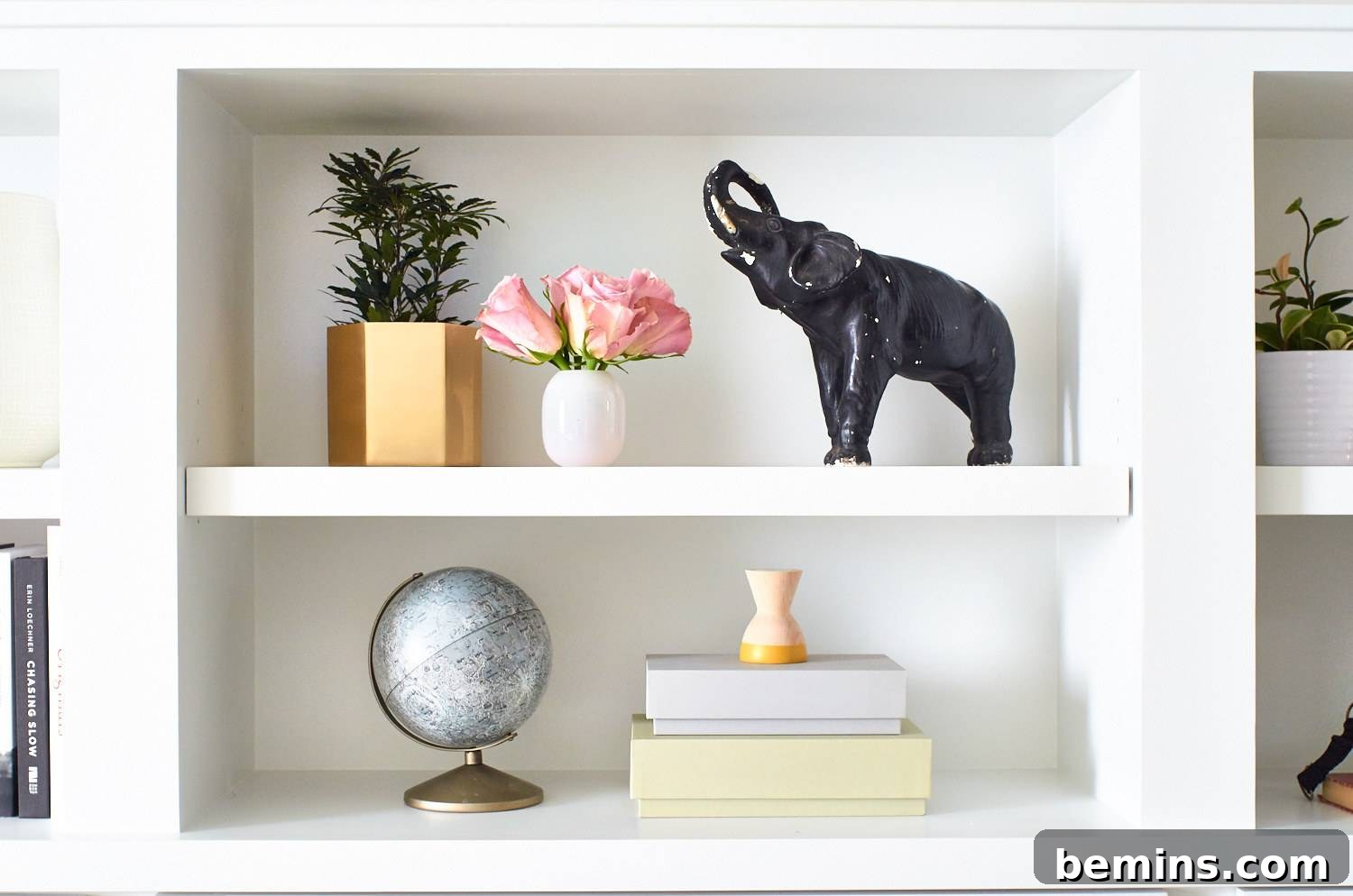 A white wall shelf adorned with a globe and an elephant sculpture. Unique decorative items add character and charm to a room.