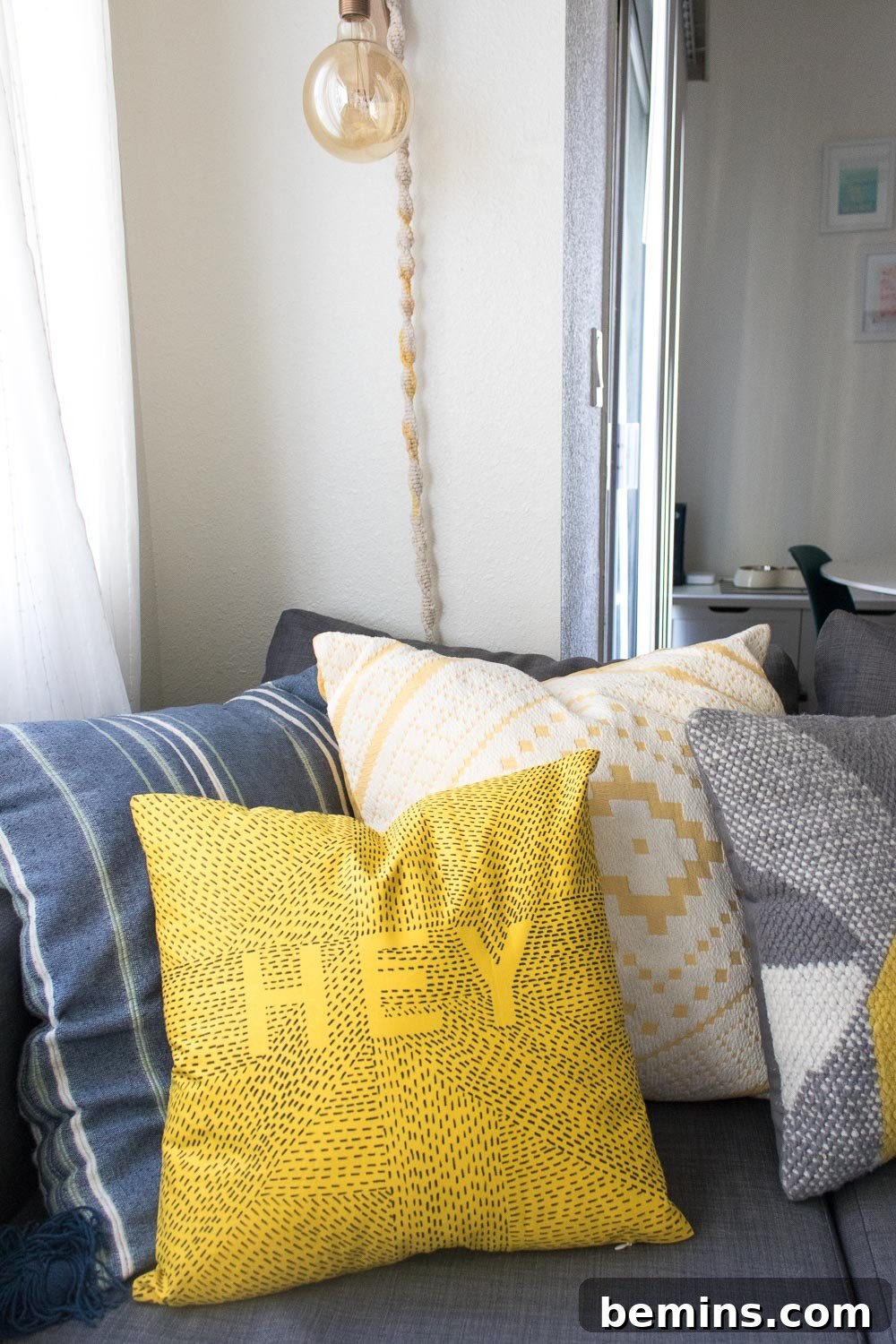 Several pillows sitting on a couch. A typographic throw pillow is prominently displayed.