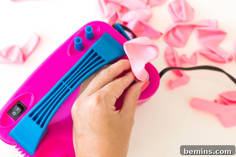 Inflating a pale pink balloon using a balloon pump